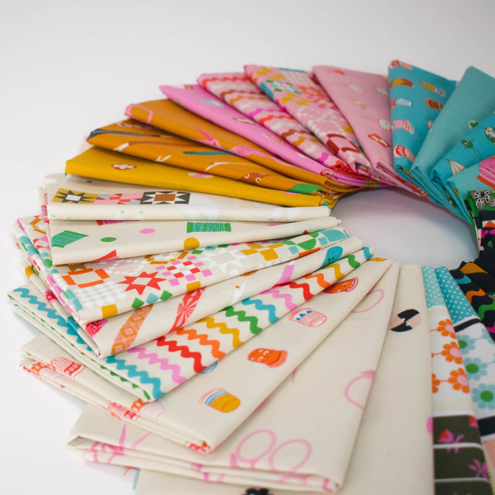 A circular arrangement of folded fabric swatches with various colorful sewing notion themed patterns, including scissors, stripes, quilt blocks, thimbles, and other fun illustrations, displayed on a clean white background.