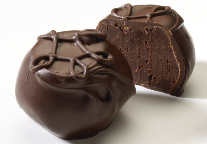 Two pieces of dark chocolate truffles with a raspberry purée filling, coated with a glazing chocolate on top.