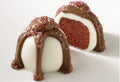 A chocolate truffle with a white and red velvet cake-like filling, coated with white chocolate, and dusted with sparkling sugar on top.
