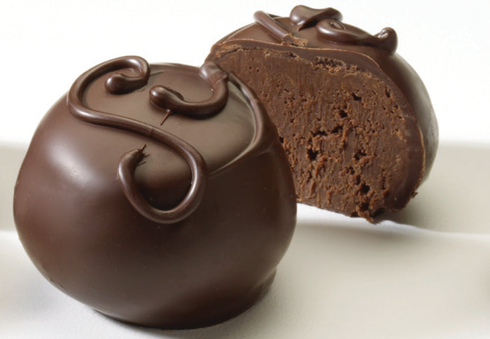 Two pieces of chocolate truffles with a smooth, dark chocolate coating and decorative toppings.