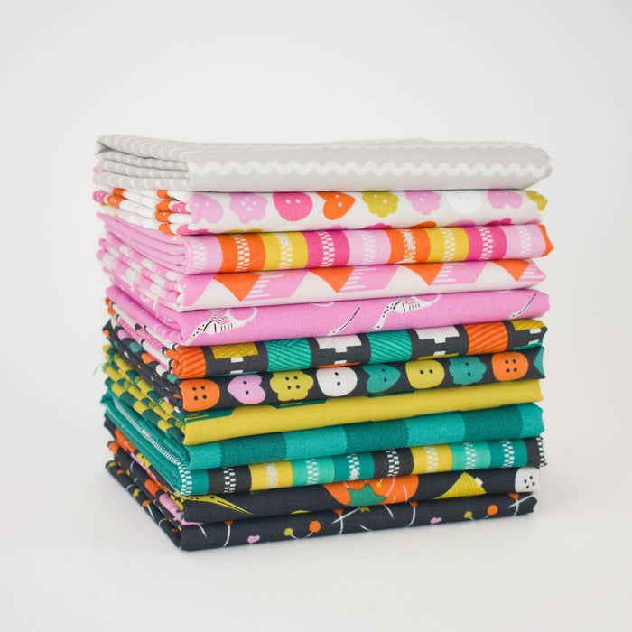 A stack of folded fabric pieces in various colorful sewing themed patterns, including pink, orange, green, black, and white, arranged neatly on a white background.