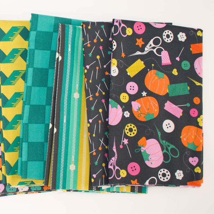 A stack of colorful patterned fabric swatches fanned out on a white background, including green-yellow geometric designs, teal zipper stripes, and a black fabric with tomato pincushions pumpkins and sewing-themed illustrations.