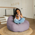 Child sitting on a large purple bean bag chair in a home setting. #color_lilac-teddy-boucle