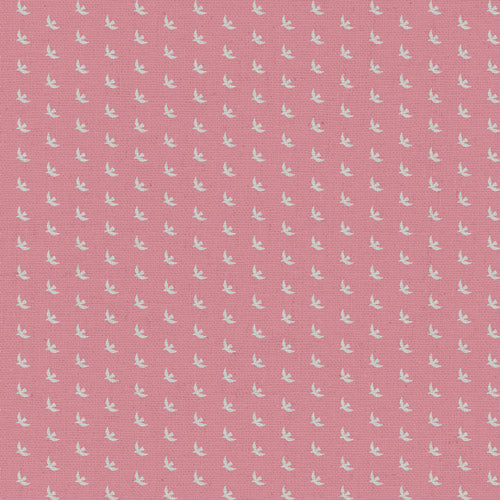 A close-up of a pink fabric featuring a repeating small white bird pattern.