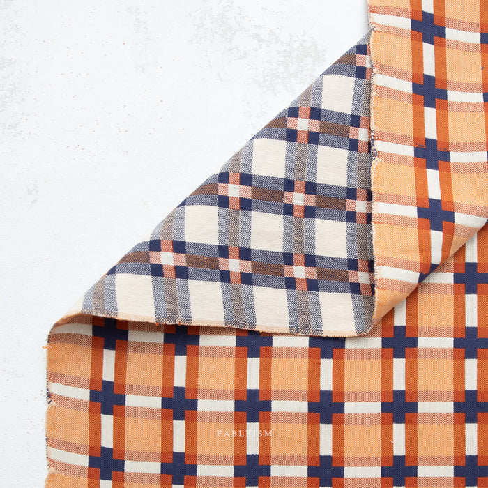 Plaid fabric with orange, blue, and beige pattern on a white background