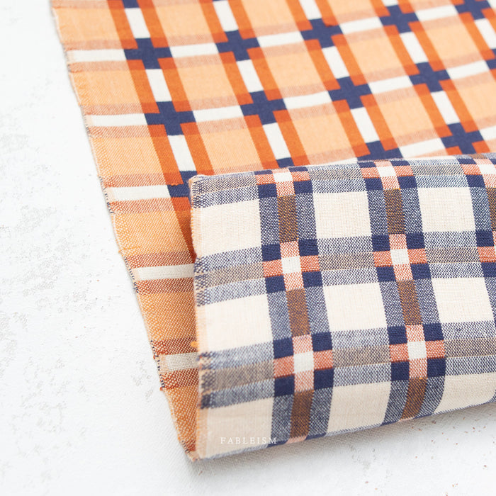 Reversible plaid fabrics in orange and blue, and beige and brown on a white background