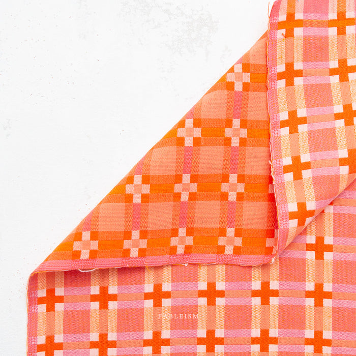 Close-up of orange and pink checkered fabric on white background.