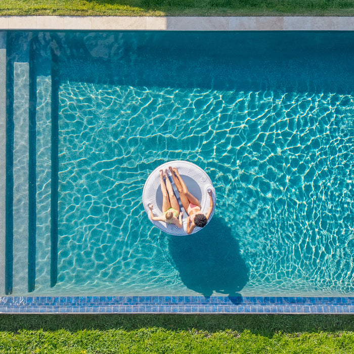 Two people lying on a inflatable ring in a pool #color_weekend-navy-stripe-olefin