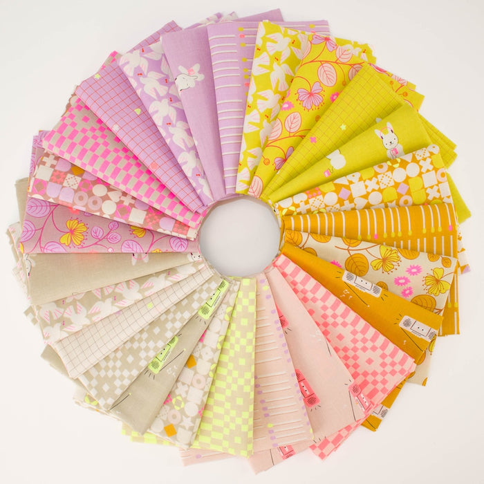 A circular arrangement of folded fabric swatches in pastel and bright colors, including pink, yellow, lavender, beige, and white, with floral and checkered patterns, displayed on a white background.