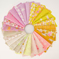 A circular arrangement of folded fabric swatches in pastel and bright colors, including pink, yellow, lavender, beige, and white, with floral and checkered patterns, displayed on a white background.
