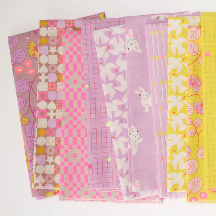 A fanned out line of nine patterned fabric swatches in pastel colors, including neon pink, purple, neon yellow, featuring various geometric, floral, and bunny motifs on a white background.