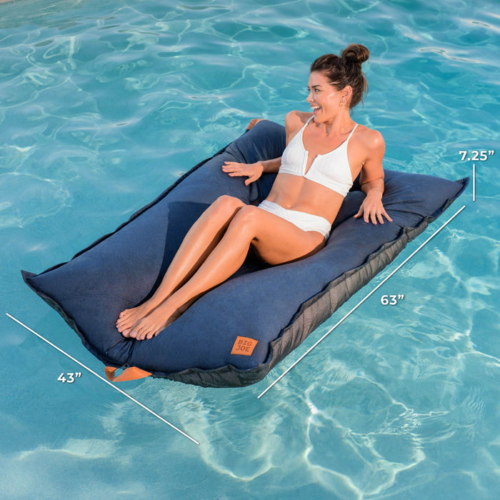 Woman sitting on a blue inflatable lounge in clear blue water with measurements displayed. #color_harbor-blue-sunbrella-fabric