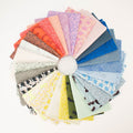 A circular arrangement of folded fabric swatches in many colors and abstract patterns, displayed on a white background.