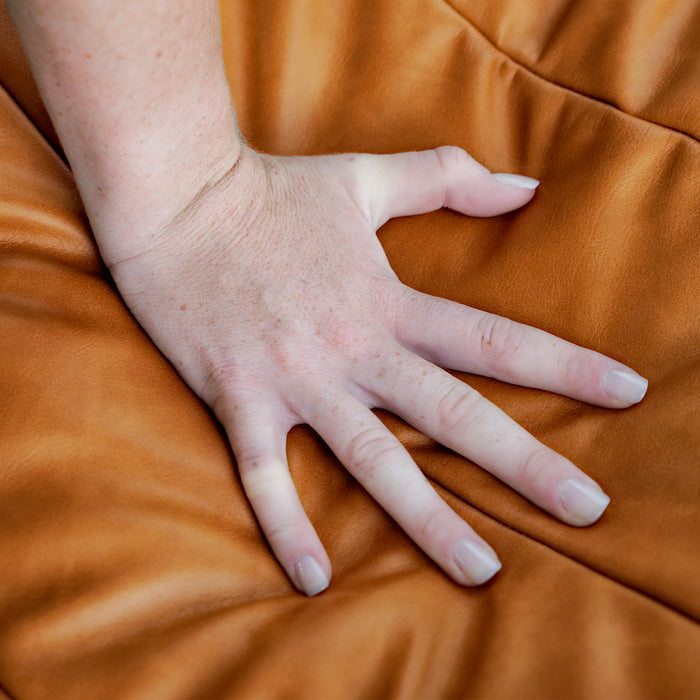 Hand resting on a brown fabric surface #color_copper-harbor-premium-vegan-leather