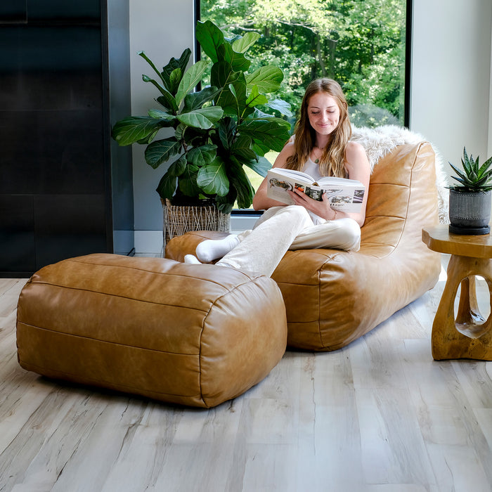 Woman reading a magazine on a tan bean bag chair in a modern living room. #color_copper-harbor-premium-vegan-leather