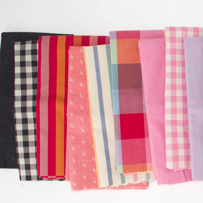 A fan arrangement of multiple fabric swatches in various patterns and colors, including gingham, stripes, plaid, and solid pink, red, orange, blue, and black, displayed on a clean white background.