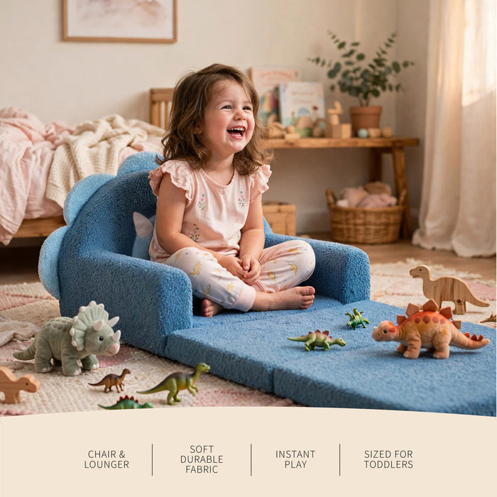 A young child sits happily in a blue plush toddler chair lounger on a carpeted floor, surrounded by dinosaur toys in a softly lit nursery. Text at the bottom highlights the chair's features: chair & lounger, soft durable fabric, instant play, and sized for toddlers. #style_blue-dinosaur