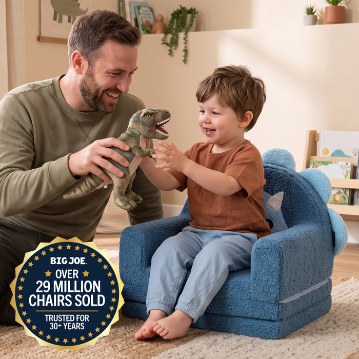 A man and a young boy smile and play together in a child-sized blue plush chair. The boy holds a green dinosaur toy, and a large gold and blue badge in the lower left reads 'BIG JOE OVER 29 MILLION CHAIRS SOLD TRUSTED FOR 30+ YEARS'. #style_blue-dinosaur