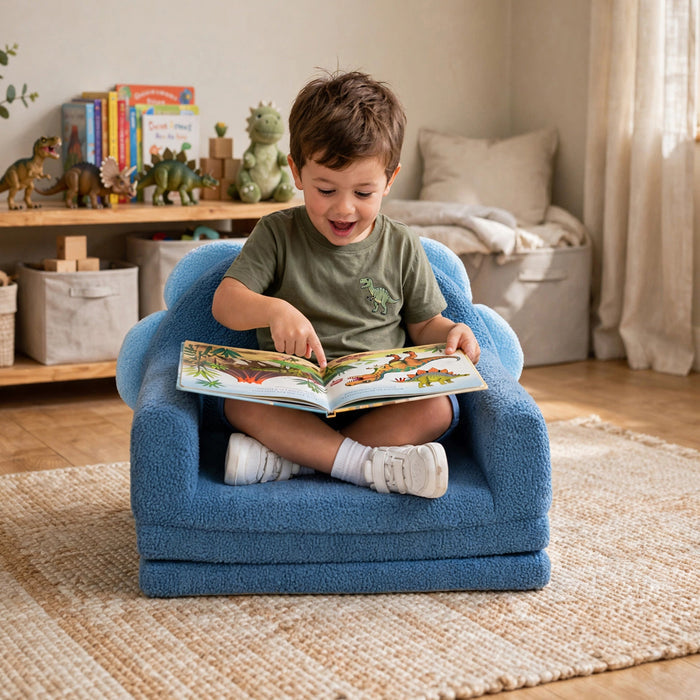A young child sitting cross-legged in a small blue plush armchair, reading a colorful children's book in a softly lit playroom. #style_blue-dinosaur