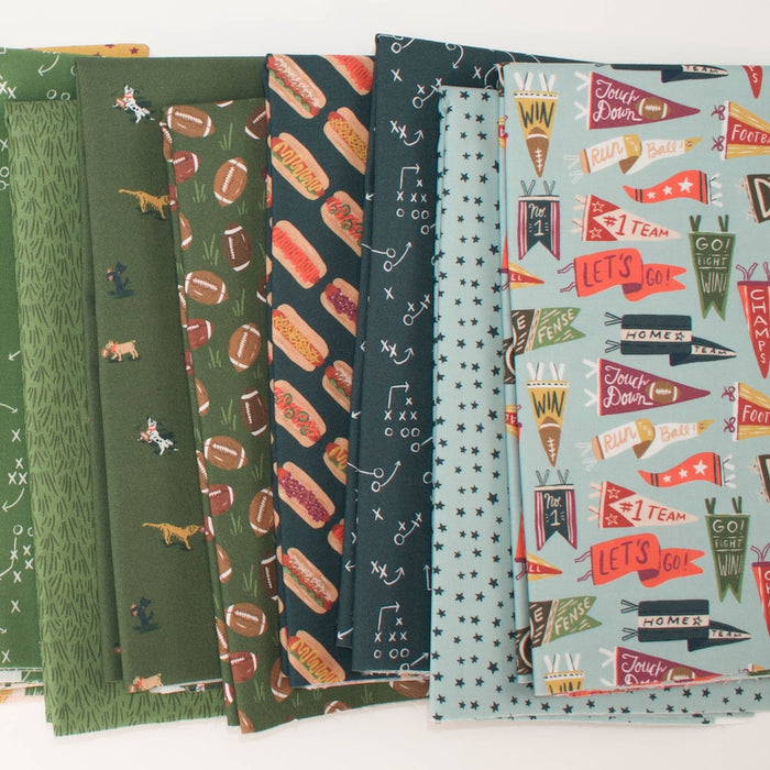 A stack of patterned fabric swatches fanned out on a white background, featuring football-themed designs including dogs, footballs, flags, and sports motifs in green, navy, light blue, and red.