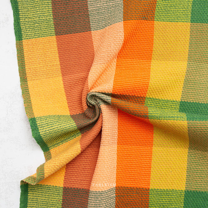 Close-up of a checkered fabric with orange, yellow, and green colors.