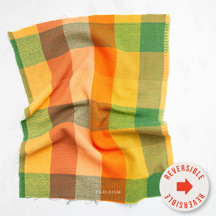 Yellow, green, and orange checkered fabric with reversible design on a white background