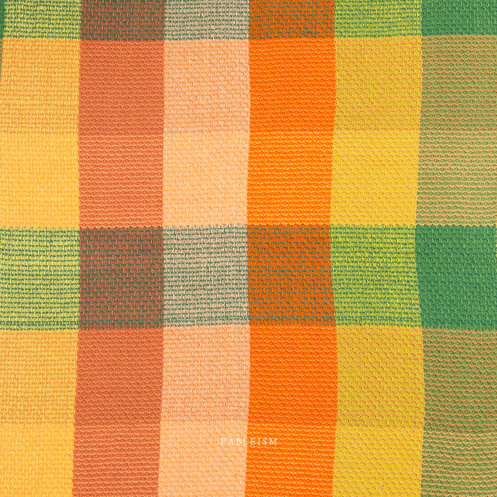 A close-up of a woven fabric with a plaid pattern in vertical stripes of yellow, orange, peach, and green.