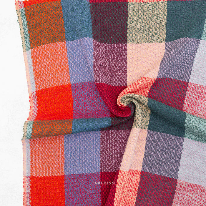 Multicolored checkered fabric with Fableism brand name on a white background