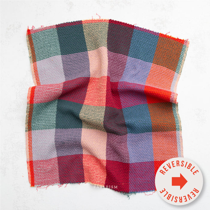 Reversible checkered fabric swatch with a 'reversible' label on a white background